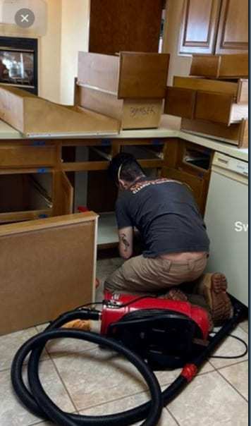 Technician extracting water where kitchen base cabinets were removed