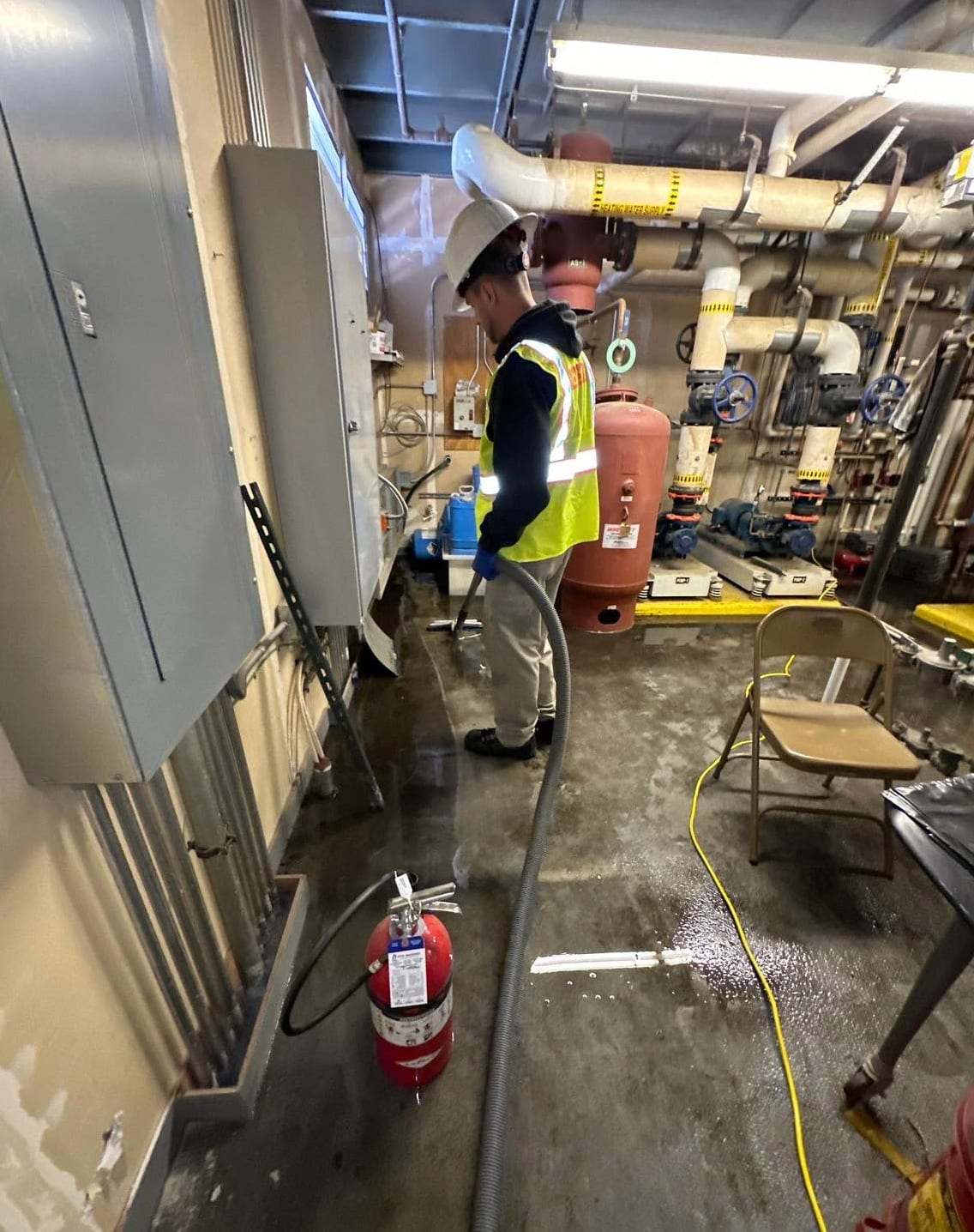 Technician extracting water in a mechanical room