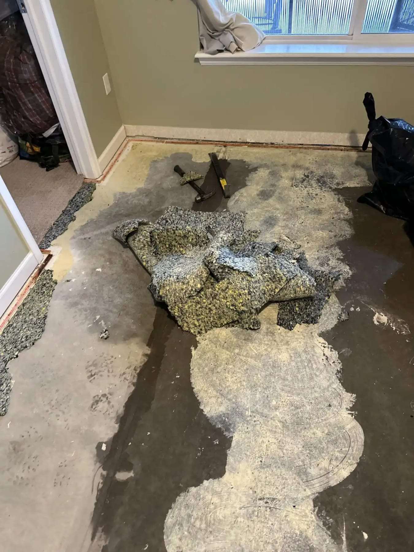 Wet carpet pad pulled up and piled on a concrete floor